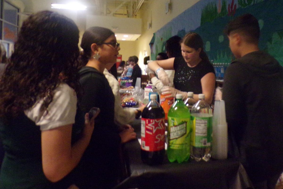 SODA SERVER 
Anna Siegmund hands out drinks and Italian sodas to students. ASB members like Anna are required to volunteer for at least 30 minutes every dance to help out. Anna commented, “It was kinda chaotic as when I was serving out Italian sodas. Everything was happening all at once.”